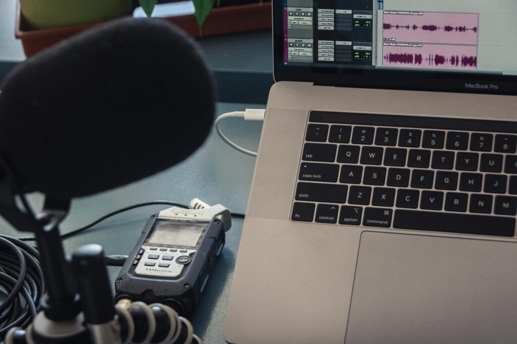Microphone and laptop setup for audio recording in a studio environment.