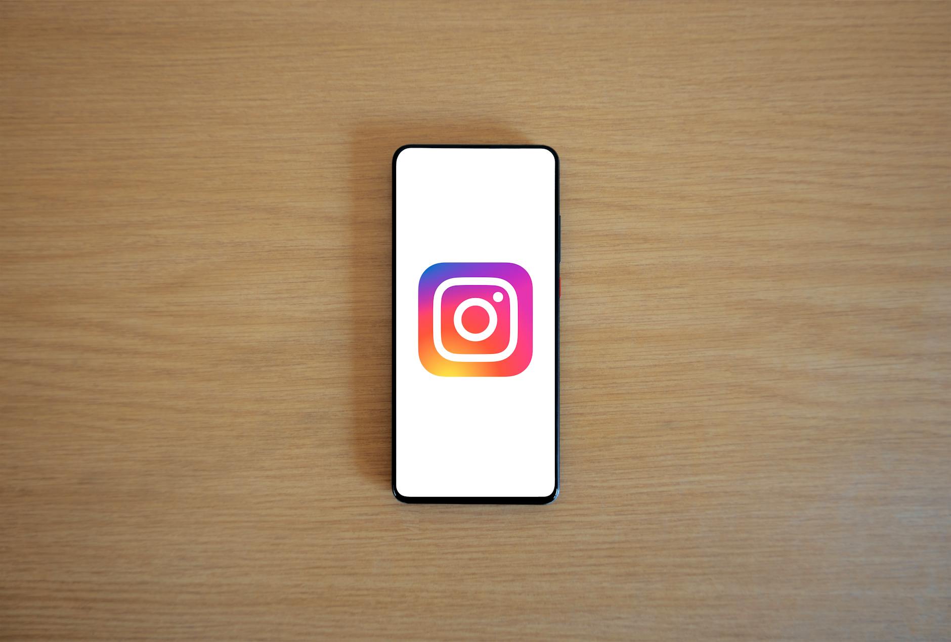 A smartphone with the Instagram logo on display, placed on a wooden surface. Perfect for technology and social media themes.