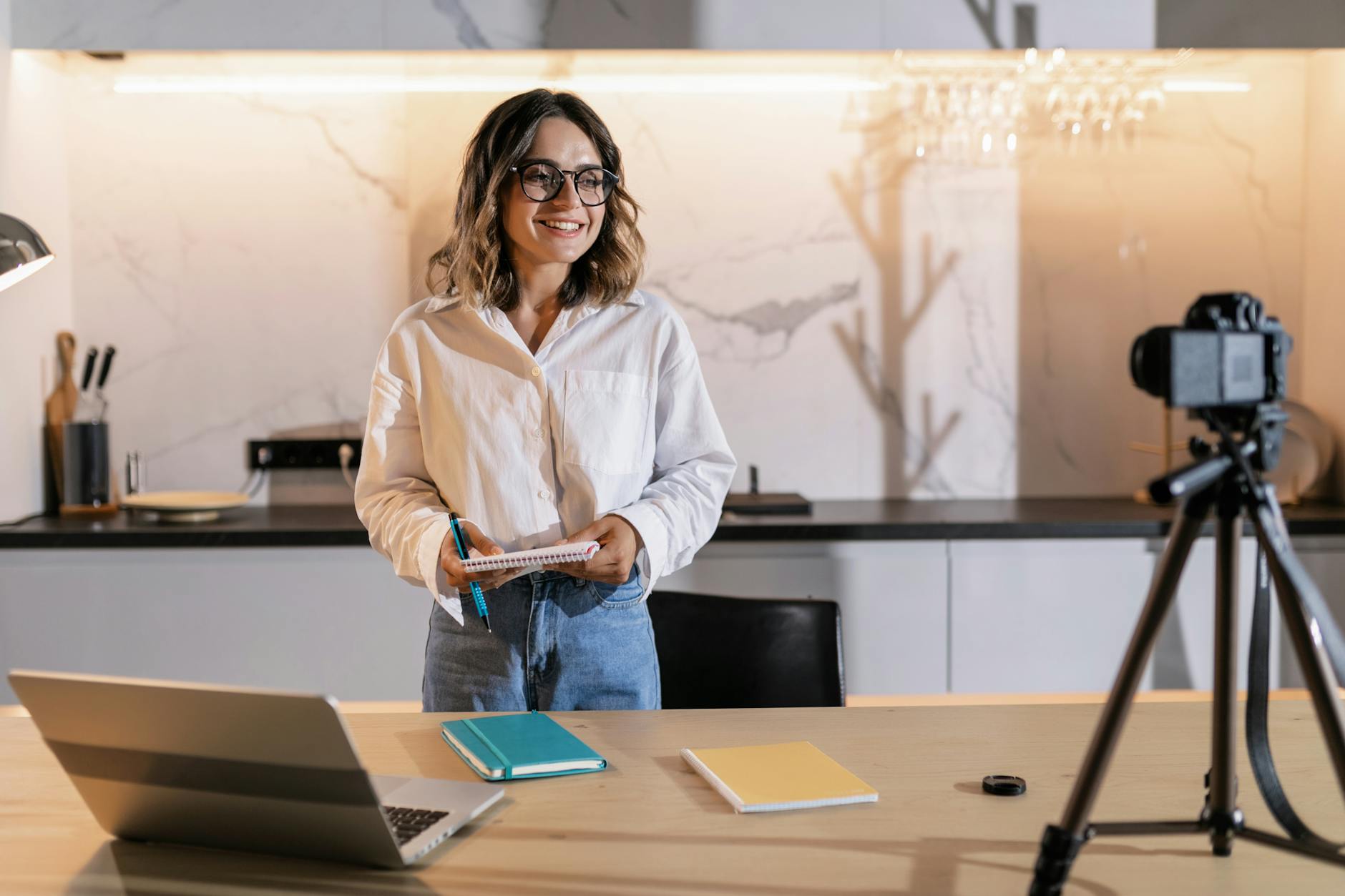 Professional woman smiling while holding a notebook in a modern kitchen setting.